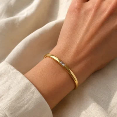 Pulseira rígida dourada com zircónia quadrada usada no pulso