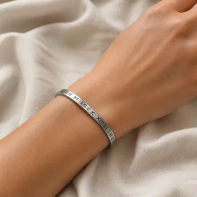 Pulseira prateada com números romanos usada no pulso