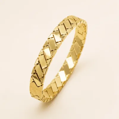 Pulseira dourada de elos geométricos entrelaçados em estúdio