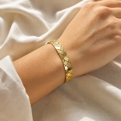 Pulseira dourada de elos geométricos usada no pulso