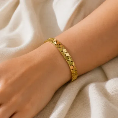 Pulseira dourada com elos trevo usada no pulso