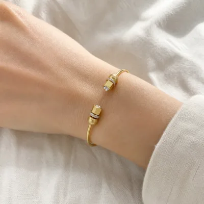Bracelete dourado aberto com cristais usado no pulso