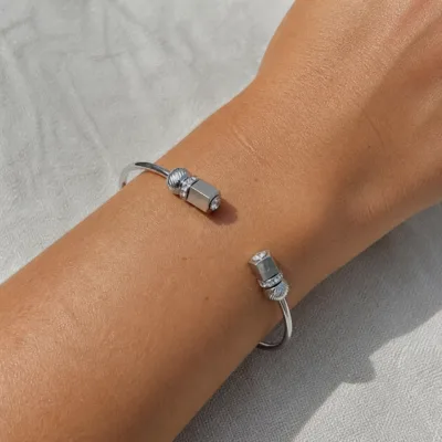 Bracelete prateado aberto com cristais usado no pulso