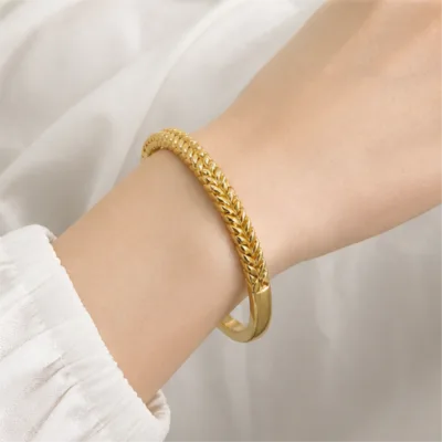 Gold-tone braided bangle 84826 worn on the wrist