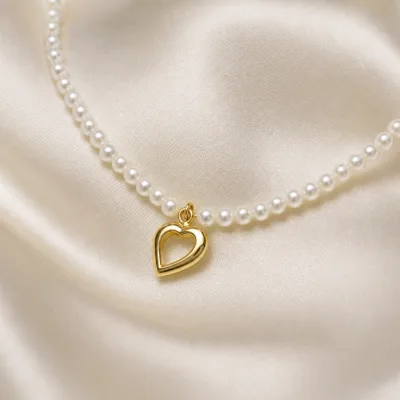 Detalhe do colar de pérolas com pendente de coração dourado