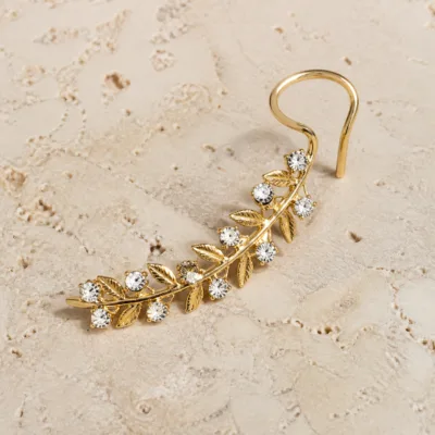 Ear cuff dourado em forma de ramo com folhas e cristais brancos