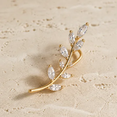 Ear cuff dourado curvo com cristais brancos em forma de gota