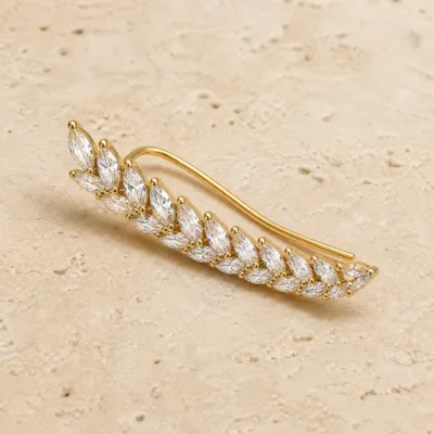 Ear climber dourado curvo com cristais brancos em forma de folha
