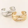 Pulseiras cuff prateada e dourada com bandas entrelaçadas