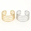 Pulseiras cuff dourada e prateada com quatro bandas paralelas