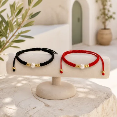 Pulseiras preta e vermelha com pérola num expositor de joalharia