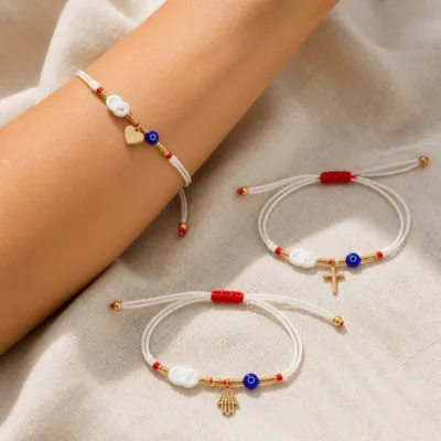 Pulseiras brancas com olho azul e amuletos dourados em ambiente lifestyle