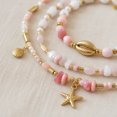 Pormenor das missangas rosa e brancas com motivos marinhos e do pendente dourado