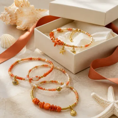 Pulseira dourada com missangas coral, pêssego e brancas com motivos marinhos em caixa de joalharia