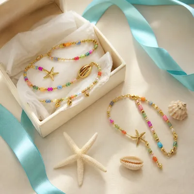 Pulseira dourada com missangas multicolores com motivos marinhos em caixa de joalharia