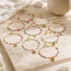 Pulseira dourada com missangas multicolores com motivos marinhos sobre fundo claro