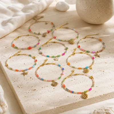 Pulseira dourada com missangas multicolores com motivos marinhos sobre fundo claro