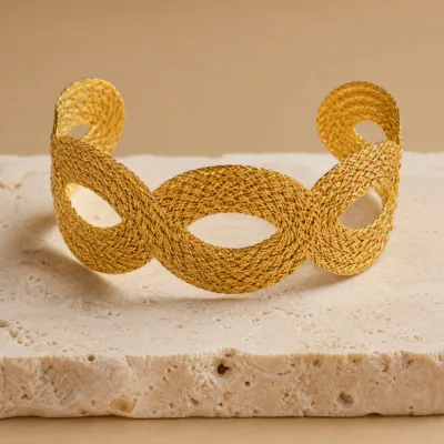 Pulseira larga dourada com textura de malha e elos entrançados