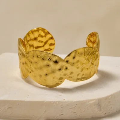 Pulseira larga dourada de folhas sobrepostas com textura martelada