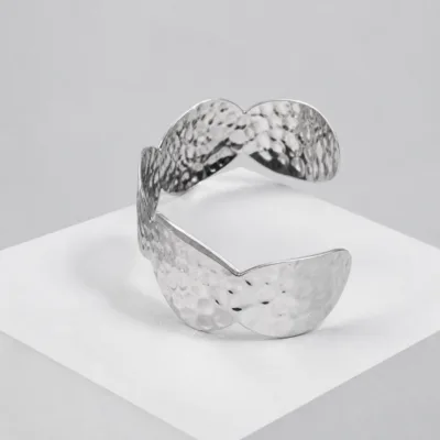 Pulseira larga prateada de folhas marteladas sobre pedestal