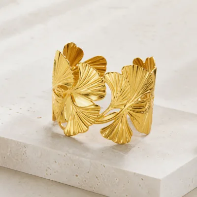 Bracelete dourado com folhas sobre pedestal de pedra clara