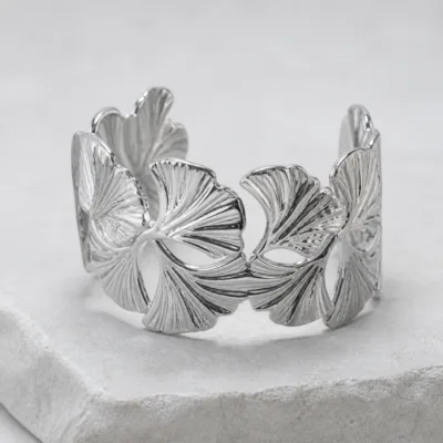 Bracelete prateado com folhas sobre pedestal de pedra clara