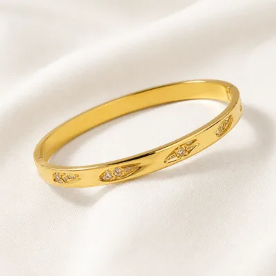 Bracelete dourado com folhas sobre linho claro