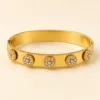 Bracelete dourado largo com medalhões florais e cristais