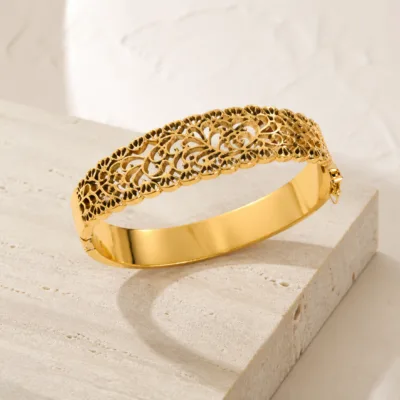 Bracelete dourado vazado sobre pedra clara