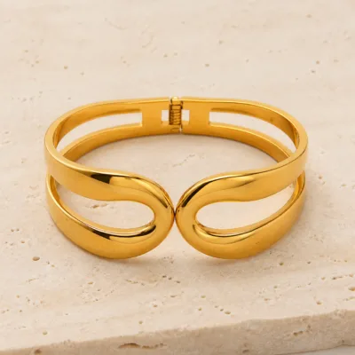 Bracelete dourado de laço duplo sobre pedra clara