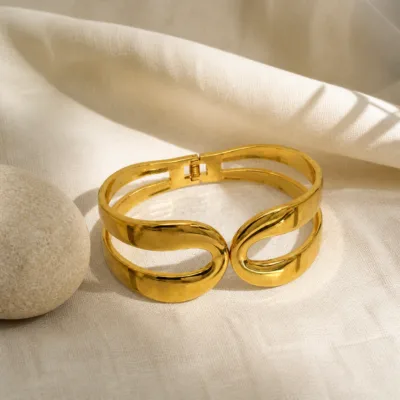 Bracelete dourado em aço inoxidável sobre linho