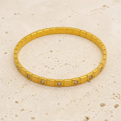 Pulseira dourada elástica sobre pedra clara