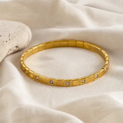 Pulseira dourada com cristais sobre linho