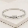Bracelete prateado com cristais e detalhe frontal em fivela