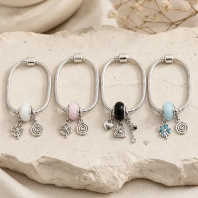 Quatro pulseiras de charms em aço com contas branca, rosa, preta e azul
