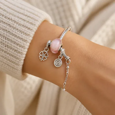Pulseira de charms com conta rosa-claro usada no pulso
