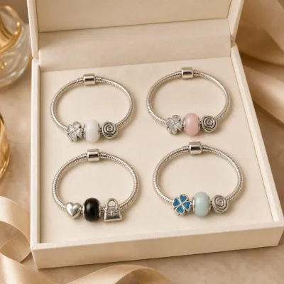 Quatro pulseiras de charms em aço numa caixa de joalharia