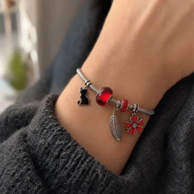 Pulseira de charms vermelha com gato e flor usada no pulso