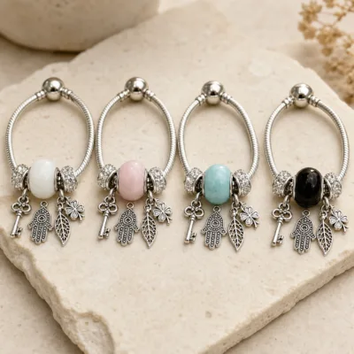 Quatro pulseiras de charms com chave nas cores branco, rosa, turquesa e preto