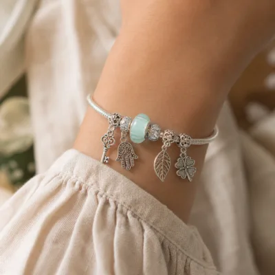 Pulseira de charms turquesa com chave e mão usada no pulso