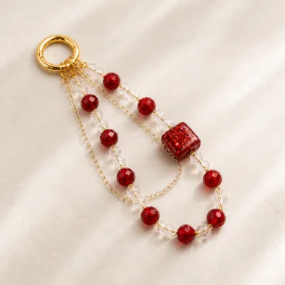 Pulseira vermelha para telemóvel com contas facetadas e corrente dourada