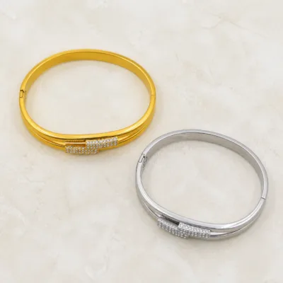 Braceletes dourado e prateado vistos de cima sobre pedra clara