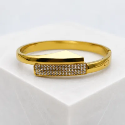 Bracelete dourado com cristais sobre pedestal claro