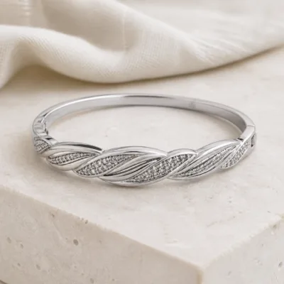 Bracelete prateado entrançado sobre pedestal claro