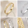 Pulseira Rígida em Aço com Padrão Floral Vazado — Dourado