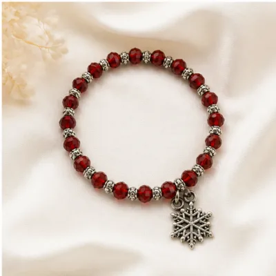 Pulseira vermelha de cristais com floco de neve sobre tecido claro