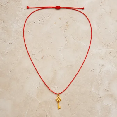 Colar vermelho com pendente de chave dourada