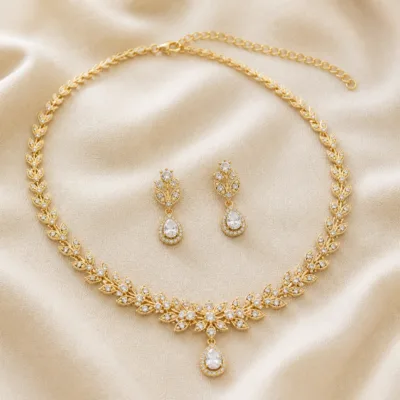 Conjunto dourado de colar e brincos disposto sobre tecido claro