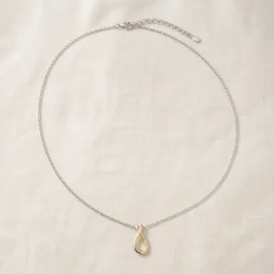 Colar em aço com pendente bicolor sobre tecido claro