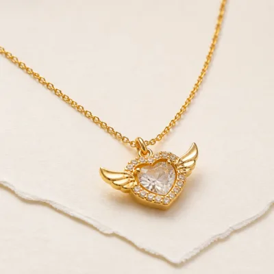 Colar dourado com coração alado e cristal